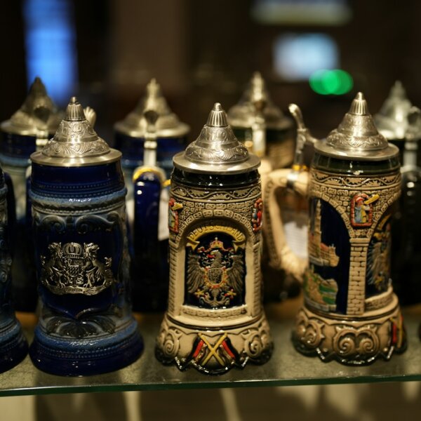 a row of beer mugs sitting on top of a glass shelf